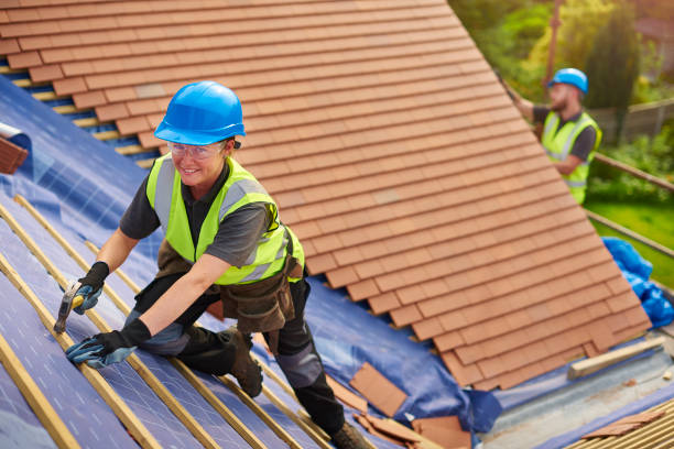 a female roofer nails on the roof tiles with her colleague